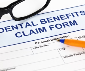 A dental benefits claim form with a pen and pair of glasses