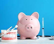 Piggy bank next to model teeth and other medical equipment