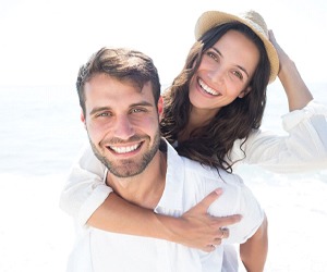 couple smiling on the beach after getting smile makeovers in Plano