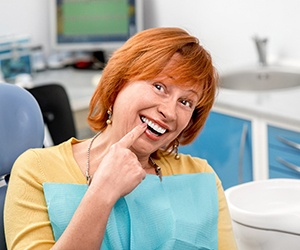 An elderly woman pointing at her all-on-4 dental implants