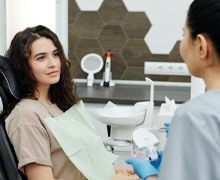 Woman speaking with cosmetic dentist, and crown being placed