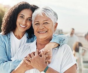 a mature woman with dentures smiling with a family member