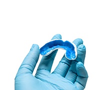 Emergency dentist in Plano holding a custom mouthguard