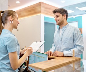 patient talking to front desk at dentist’s office 