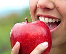 Closeup of patient with dental implants in Plano eating an apple