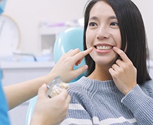 Young woman pointing to her new dental implants in Plano