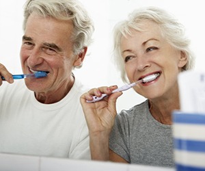 couple practicing dental implant care in Plano by brushing their teeth 