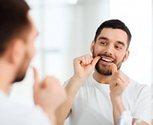 man flossing in front of a mirror 