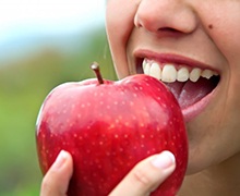  person biting into a red apple 