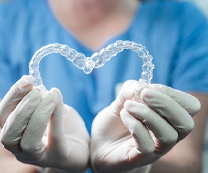 Plano cosmetic dentist holding Invisalign aligners in heart shape