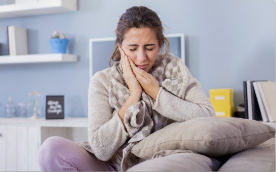 woman holding mouth in pain in Plano