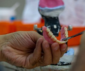 closeup of hands refining a denture 