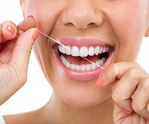 person flossing their white teeth 