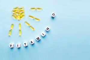 Vitamin D supplements laid out like a sun ray with cubes spelling "vitamin D" on a light blue background