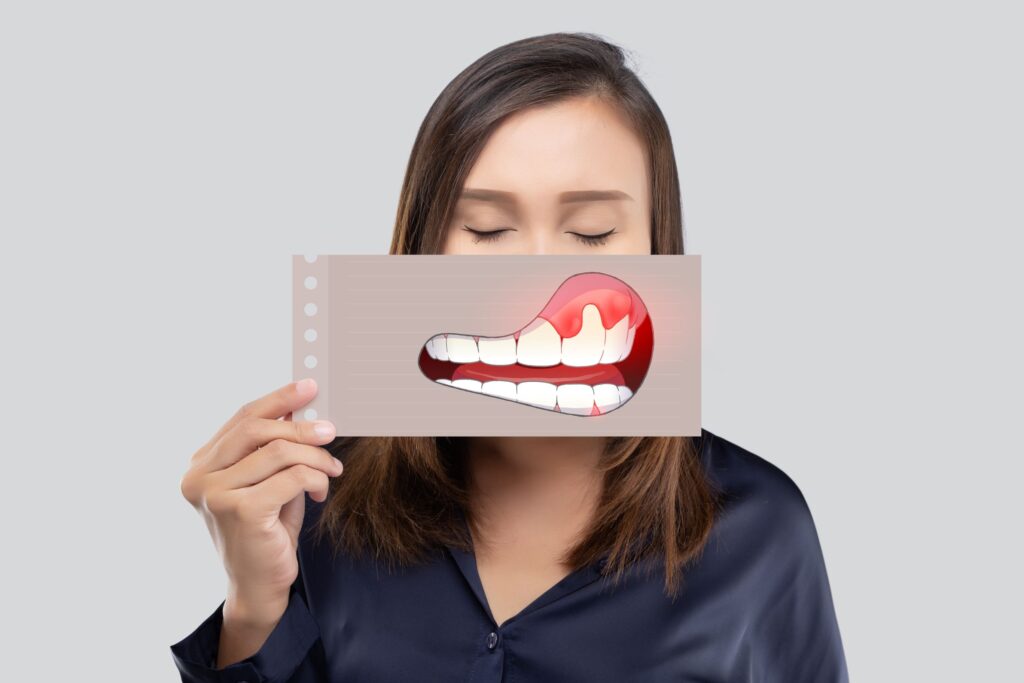 Woman with eyes closed holding picture of swollen gums over mouth