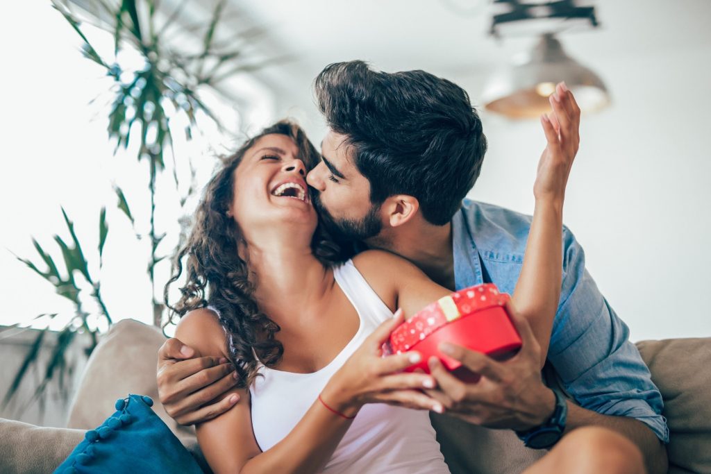 Man kissing woman on cheek while giving a present