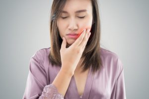 woman holding her jaw in pain